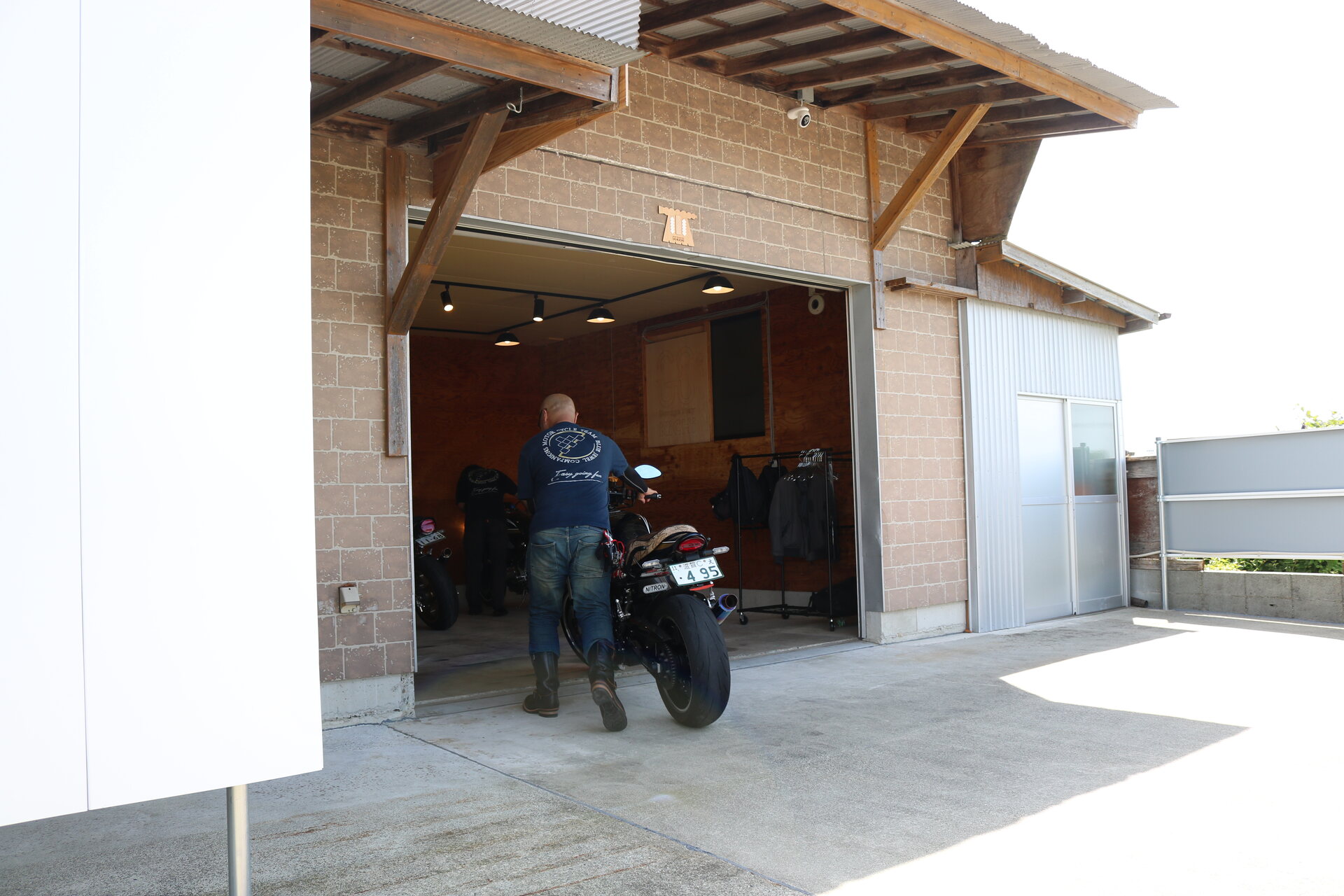 外観。シャッターを開けたガレージにバイクを入れるところ